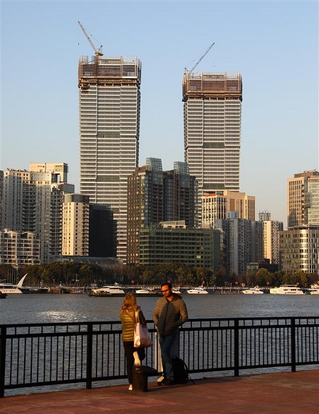 Two foreigners chat at the Huangpu riverfront in the Pudong New Area against the backdrop of Star Harbor International Center across the river. (Jiang Xiaowei/SHINE)