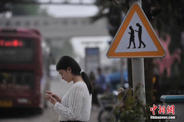 The warning sign reminds people not to look at their mobile phones when walking through a crosswalk. (Photo/Chinanews.com)