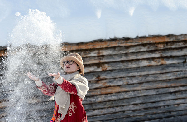 A tourist plays with snow at Hemu, which is located in the Kanas national park. (Photo/Xinhua)