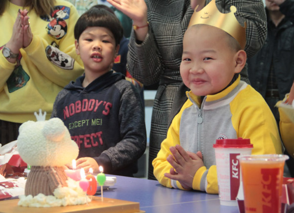 Xiaochangjiang (right) spends his first celebrated birthday at a welfare house in Qingdao, Shandong province, on Sunday. The 7-year-old became an internet sensation after photos showing him working as a courier went viral on WeChat. (Photo by ZHANG FUHONG/FOR CHINA DAILY)