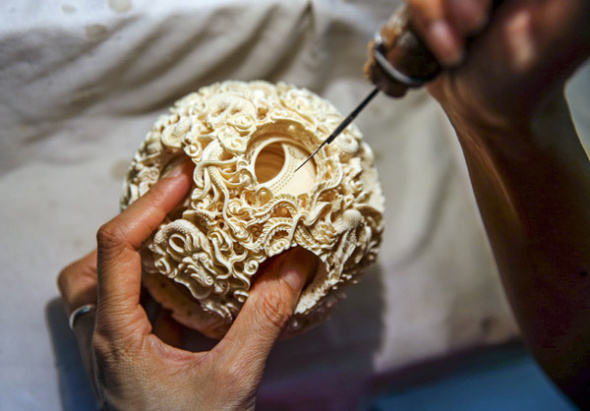 A delicate ivory sculpture is carved at a shop in Guangzhou, Guangdong province, last year. (Photo by ZOU HONG/CHINA DAILY)