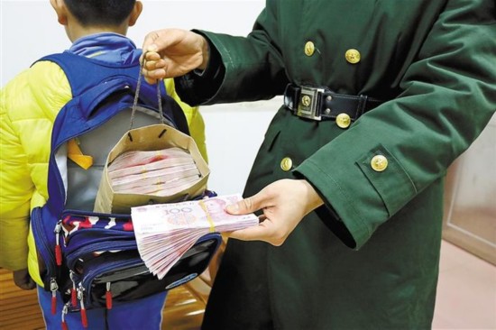 An 11-year-old pupil carrying 140,000 yuan ($21,756) in cash in his schoolbag was spotted at a checkpoint on Chung Ying Street in Shenzhen, Jan 9, 2017. (Photo/Shenzhen Evening News)