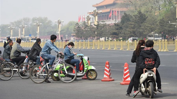 People riding electric bikes wait at a traffic light. (Photo/CGTN)