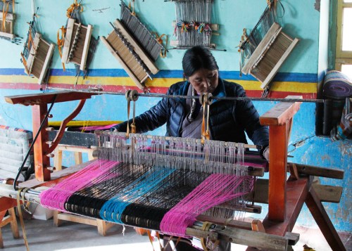 Lhoka native Pema Dekyi at her loom at Tibet Huaji Fashion Co. (Photo/China Daily)