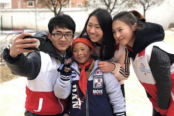 Volunteers pose with 8-year-old Wang Fuman after helping him put on a pair of gloves.  (Photo‍/Chinadaily)