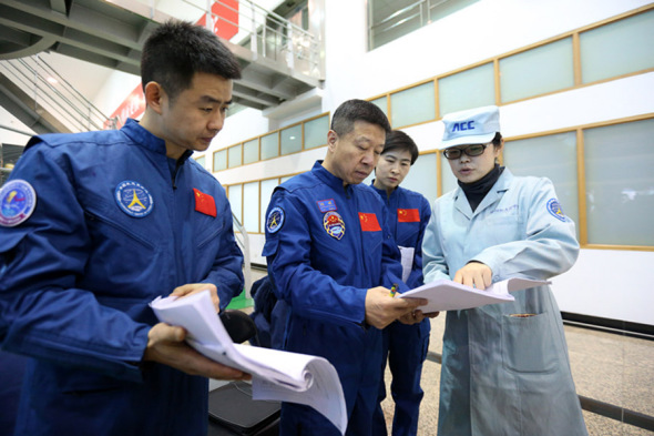 Chen Dong, Liu Wang and Liu Yang talk with a team member during flight training at the center. (Feng Yongbin/China Daily)