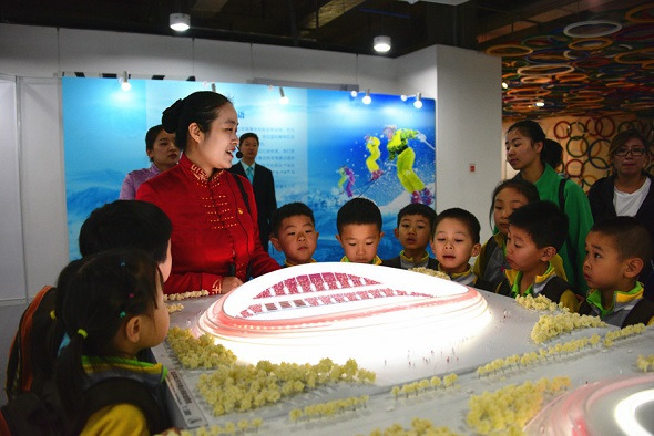 A guide describes a model of the National Speed Skating Oval, dubbed the Ice Ribbon, at a project construction display in April. The venue is being built in Beijing for the 2022 Winter Olympics. (Photo by Ma Zhijiang/For China Daily)