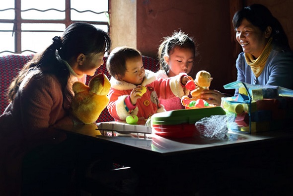 Wu Lumei shows Li Binying how to play with an educational toy. (Photo by Wang Jing/China Daily)