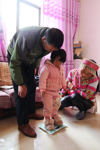 Zhan Jialu weighs Zheng Menghan. (Photo by Wang Jing/China Daily)