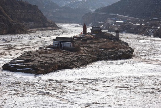 Flowing ice covers the Yellow River in Jixian county, Shanxi province, on Wednesday. The section has seen an increase in ice due to the cold weather. (Photo by Lyu Guming/Xinhua)