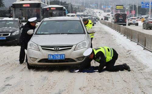 Policemen help push a car go forward on a snowy road in Wuhan, capital of Central China's Hubei Province, Jan. 27, 2018. (Photo/Xinhua)
