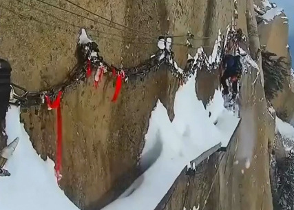 A worker sweeps snow on a treacherous walkway along cliffs on the Huashan Mountain, a scenic spot in Northwest China's Shaanxi province. (Photo/Screenshot from Pear Video)