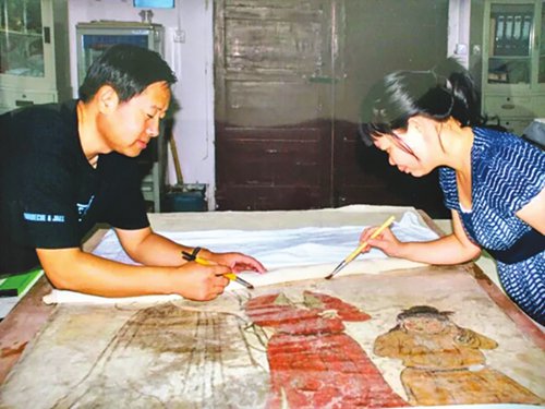 Mural of a Maidservant with a DishWang Jianqi (left) restores a mural. (Photo/Courtesy of Wang Jianqi)