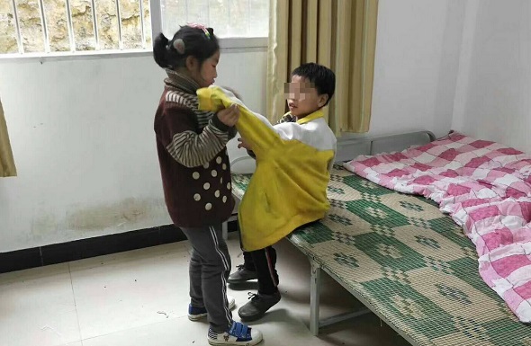 Zhou Dingshuang helps her brother put on his clothes. (Photo provided to chinadaily.com.cn)