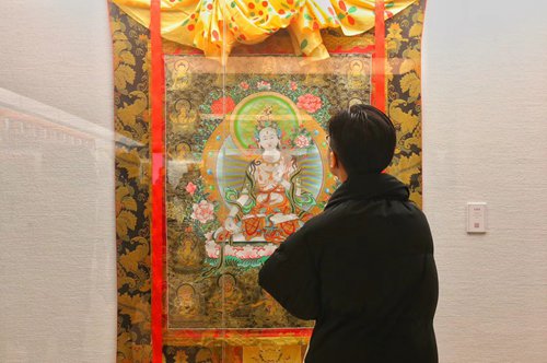 A visitor appreciates a Tibetan thangka painting at the National Art Museum of China (NAMOC) on Monday. (Photo/Courtesy of Yang Zi)