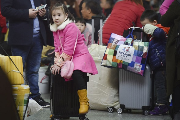 A young girl waits with her family for the train at Fuzhou Railway Station in Fujian province on Wednesday. The official Spring Festival travel season begins on Thursday. (Photo/Xinhua)