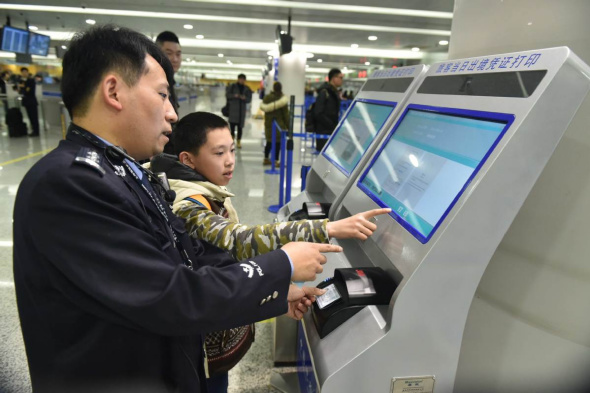 A border security officer shows how to use the self-service printing machine. (Wei Wenheng/for chinadaily.com.cn)