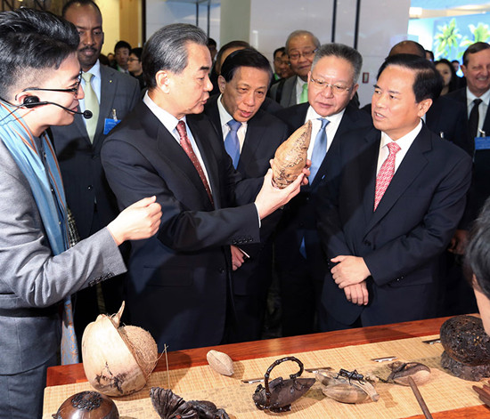 Foreign Minister Wang Yi (second from the left) learns about coconut sculpture from Liu Cigui (right), secretary of Hainan Provincial Committee of the Communist Party of China, in Beijing on Friday. Wang Zhuangfei / China Daily 