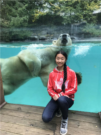 Chinese girl Zhang Jiahe poses with a polar bear while visiting a zoo in France. Photo by Herve Fabre/Provided to China Daily