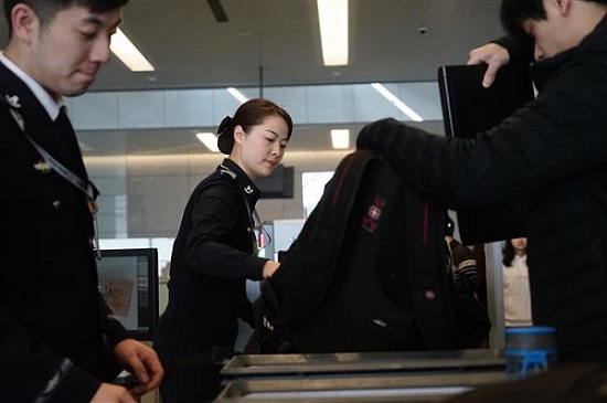 Wu Na, the leader of the No. 1 security team at the Hongqiao International Airport, checks carry-on bags on an X-ray machine. (Ti Gong)