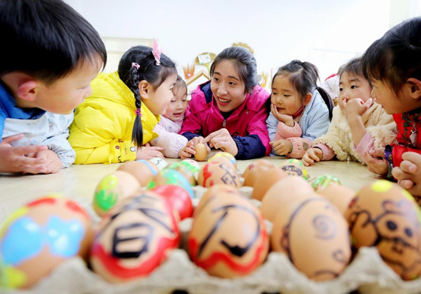Kids at a kindergarten in Jiangsu province play a game of standing spring eggs with their teacher on Spring Equinox, March 20, 2017. (Photo/Xinhua)