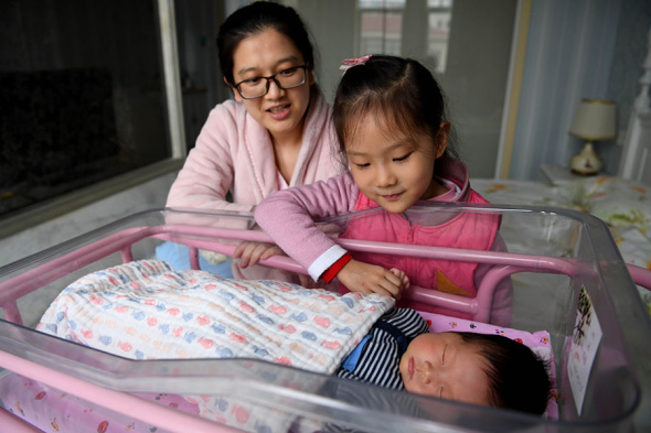 A mother and her daughter watch over the family's newborn baby at an infant healthcare center in Hefei, Anhui province, on Dec 2. LIU JUNXI/XINHUA