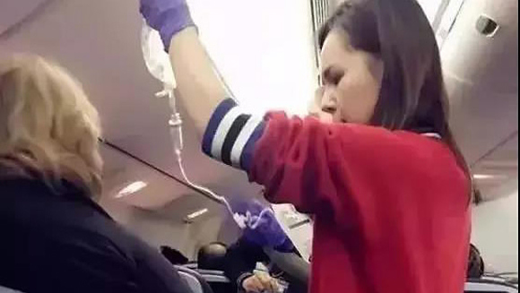 Zhao Min, 28, helps an old passenger who suffers a sudden angina attack on a flight from San Francesco to Honolulu, Jan. 10, 2018. (Photo/CGTN)