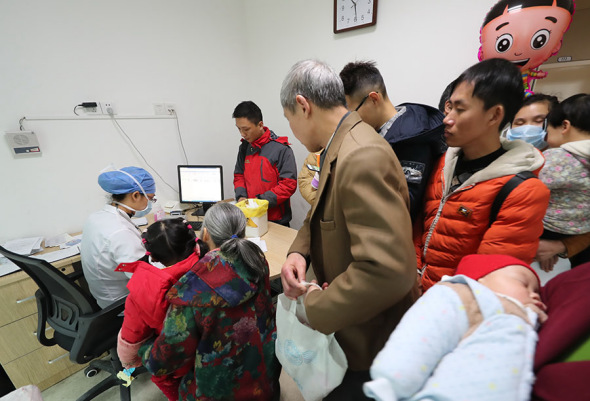 Pediatrician Wang Tianbo is surrounded by young patients and their relatives in Ningbo Women and Children's Hospital in Zhejiang province last month. ZHANG PEIJIAN/FOR CHINA DAILY