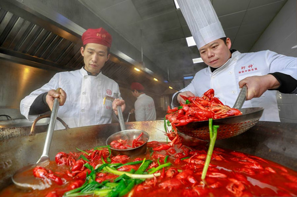 Two chefs prepare scampi dishes in Xuyu, Jiangsu. (Photo by Zhou Haijun/Xinhua)