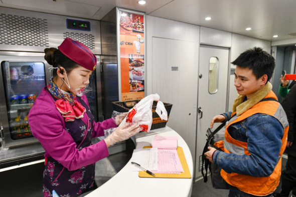  A courier delivers a food order for passengers to an attendent on a high-speed train in Chongqing on Feb 9, 2018.(Photo/Xinhua)