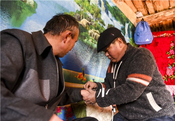 Gyens (right) inserts a drip for a herder at the man's home. (HU HUHU/XINHUA)