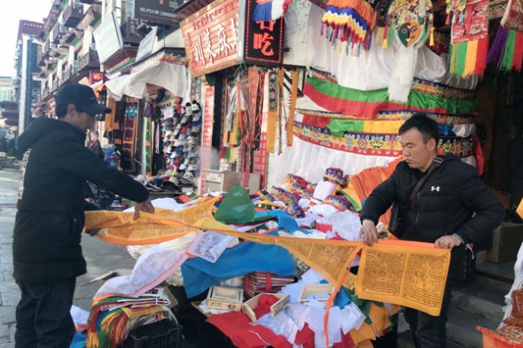 Workshop founder Galsang (right) sells prayer flags in Lhasa, the capital of the Tibet autonomous region, on Feb 8.(Photo by Da Qiong/China Daily)