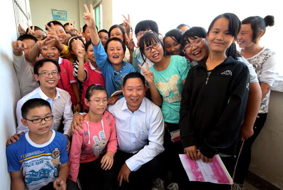 Wang Huajun, a taxi driver from Yichang, Hubei province, spends time with primary school students in an underdeveloped area. (Photo/China Daily)