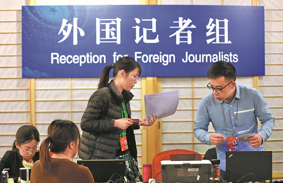 Staff members work at the media center that opened in Beijing on Tuesday for the upcoming first session of the 13th National People's Congress and first session of the 13th National Committee of the Chinese People's Political Consultative Conference, known as the two sessions. (ZHU XINGXIN / CHINA DAILY)