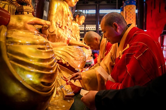 Monks work on gilding the three Buddha statues inside the main hall. (Ti Gong)
