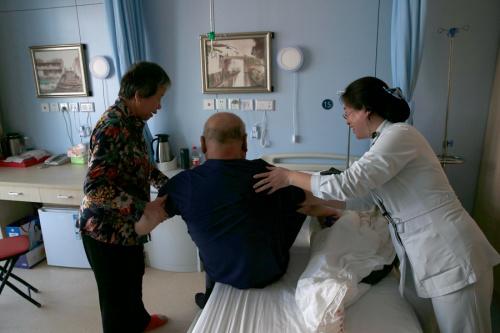 A nurse helps a patient to sit up at Peking University Shougang Hospital in Beijing. (Photo for China Daily)