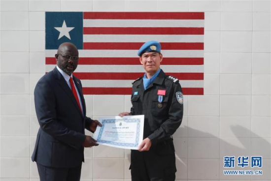 Liberian President George Weah (L) presents the National Award certificate to China's fifth peacekeeping police force in Monrovia on February 28, 2018. [Photo: Xinhua]