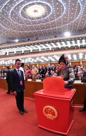 A deputy to the 13th National Peoples Congress casts her ballot on proposed amendments to the countrys Constitution at the third plenary meeting of the ongoing 13th NPC in Beijing on Sunday. (Photo/Xinhua)