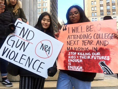 Rachel Song (left) and Katrina Taeza, both juniors at Brooklyn Technical High School, hold up signs during a rally at Borough Hall in Brooklyn on Wednesday as part of a nationwide protest against gun violence. (JUDY ZHU / CHINA DAILY)