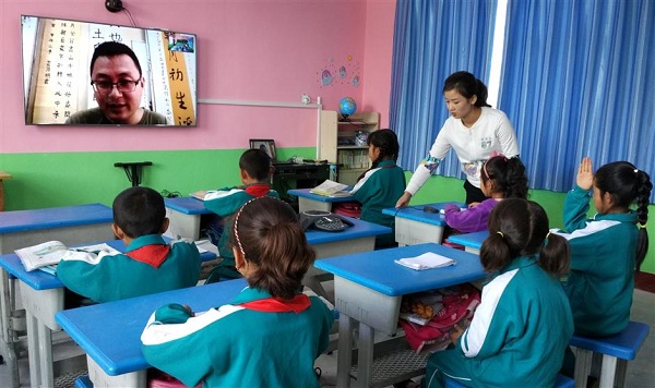 Children of Xiaxia Elementary School in Gansu Province take a class taught by a volunteer teacher live on a TV screen.(Ti Gong)