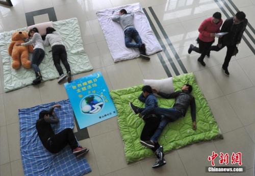 Students at Hefei University participate in a competition on sleeping postures to celebrate World Sleep Day in Hefei, East China's Anhui province, March 21, 2018.  (Photo/Chinanews.com)