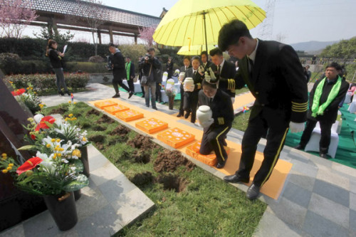 The ashes of six people, in degradable urns, are placed into holes for burial during a group green funeral at the Yinlongshan Cemetery in Nanjing, Jiangsu Province, last week. (Photo by SONG NING/FOR CHINA DAILY)