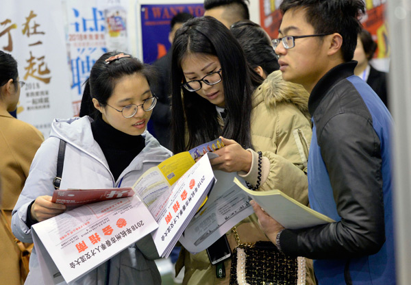 Job seekers check recruitment information at a job fair held in Hangzhou, capital of Zhejiang province. (Photo by Shi Jianxue/For China Daily)
