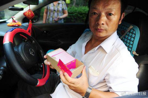 Wang Mingqing carries a stack of cards with information on his missing daughter, that he hands out to passengers in his taxi. (Photo/ Sina Weibo account of Sichuan Daily)