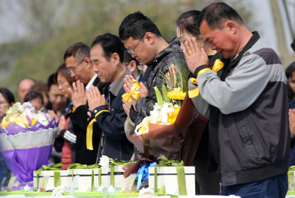 People pray in the cemetery before burying ashes under saplings on Saturday. Photo: China Daily /Wang Zhuangfei)
