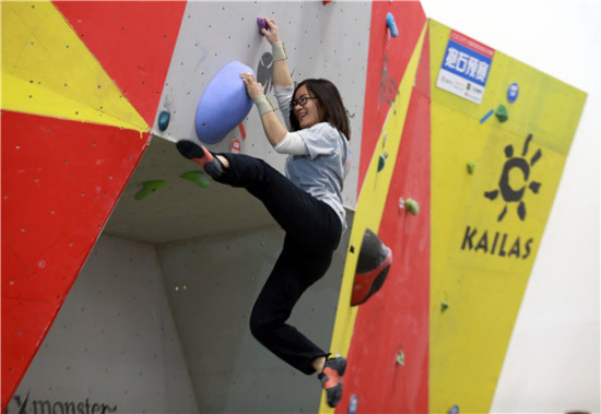 A woman climbs an artificial rock at the eighth China international mountain and winter sports machinery exposition held in Beijing. ZOU HONG/CHINA DAILY