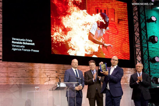 Venezuelan photographer Ronaldo Schemidt (2nd R) shows his trophy in Amsterdam, the Netherlands, on April 12, 2008. (Xinhua/Sylvia Lederer)