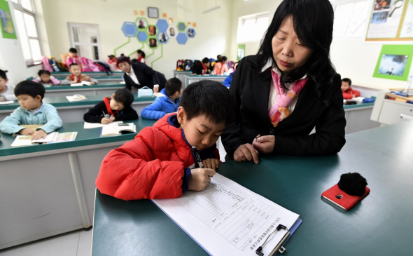 A primary school pupil in Beijing registers on the list of children waiting for their parents to pick them up after school. (Photo/Xinhua)