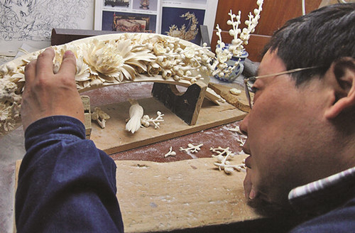 An artist carves a piece of ivory at the Beijing Ivory Carving Factory in 2013. (Photo/China Daily)