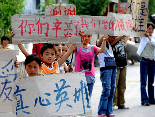 Children in quake-hit Qingchuan county hold banners reading True hero, Thank you for your efforts and I love you to welcome rescue personnel on the way leading to the county in Sichuan May 16, 2008. (Photo/Xinhua)